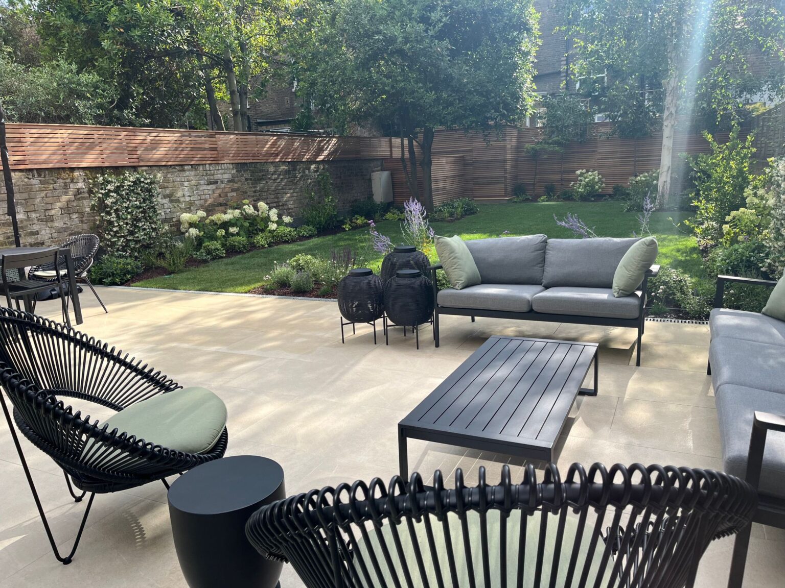 Hammersmith family garden with a stone terrace, lounge seating and layered shade planting