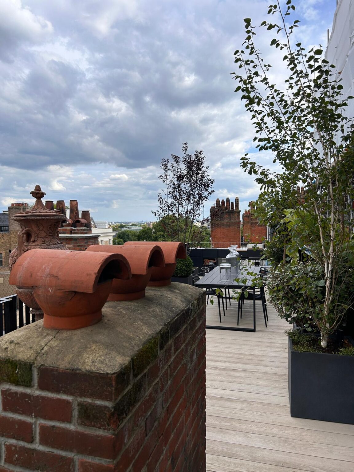 London rooftop terrace with chimney pots, planters and an outdoor dining area