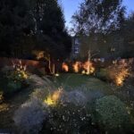 Hammersmith family garden at dusk, with warm garden lighting through layered planting