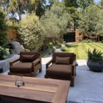 Family garden terrace with lounge chairs, a timber table, olive tree and Mediterranean-style planting