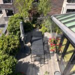 Timber-decked roof terrace with outdoor dining, multi-stem trees and planters in central London